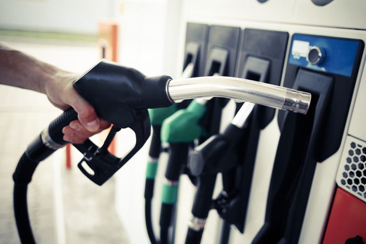 A person's hand holds a gas pump at the gas station.