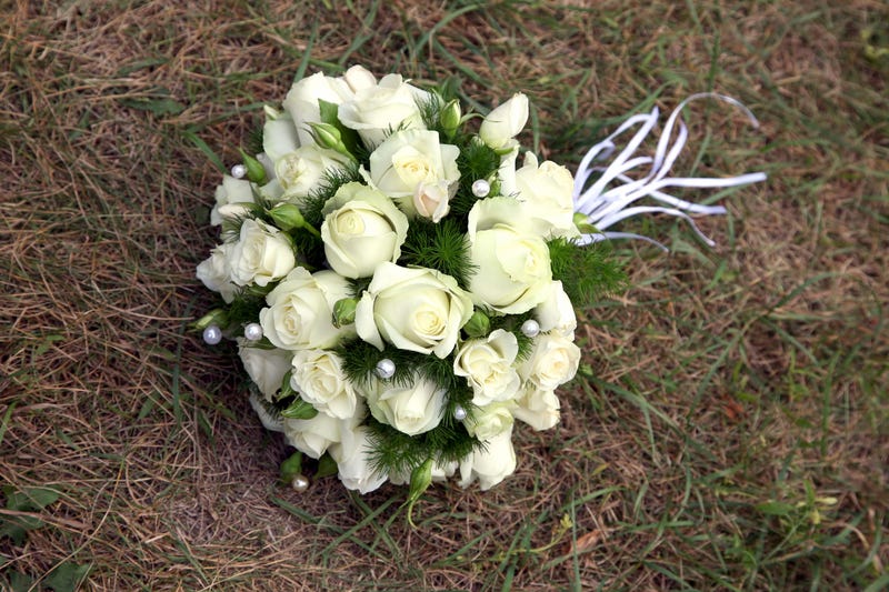 Wedding bouquet of white roses lying on the grass.
