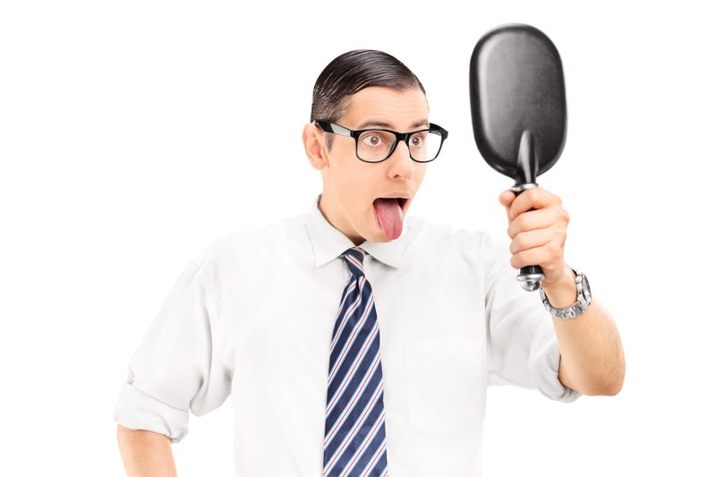 Man looking in mirror and sticking his tongue out