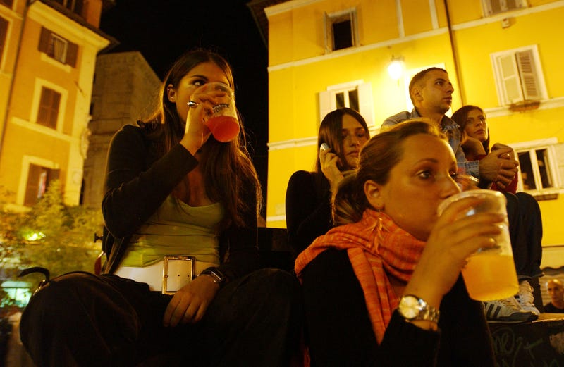  (From L-R) Virginia Recchi, 16, Violante Pasolini, 17, (front C) and Ludovica Lombardini, 17, sit as they have a drink in a square June 17, 2004 in Rome, Italy. In Rome privileged teenagers get around mainly in very expensive small cars for which they don't need a license plate or a driver's license. They all dress in the same metropolitan style, and spend most of their free time wandering around not doing much. Many teenagers' status symbols are cloths, mobile phone and accessories. Most of them have credit cards and act as if they are adults. (Photo by Marco Di Lauro/Getty Images)