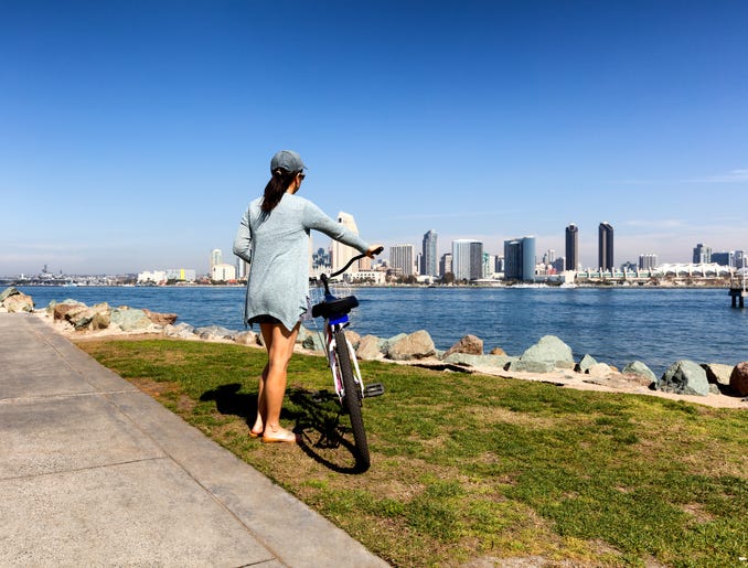 Woman with bicycle gazes at San Diego Bay