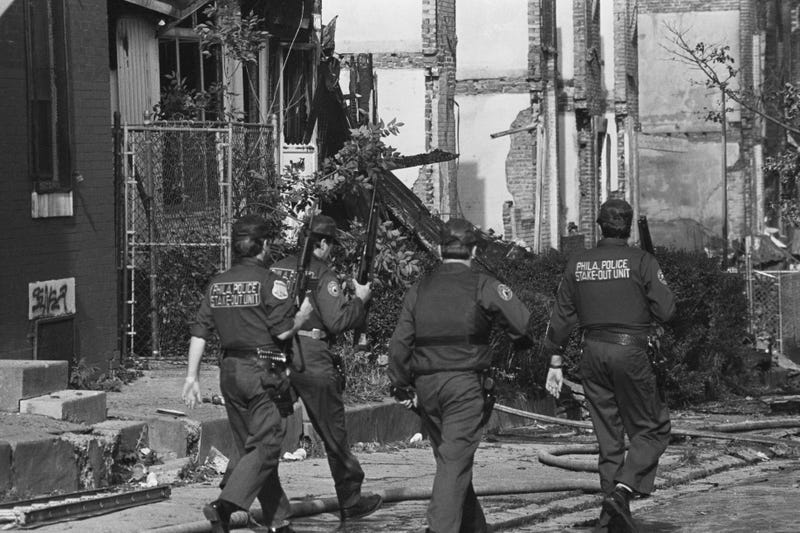 Several Philadelphia police officers stroll through the West Philadelphia neighborhood destroyed by the bombing of the MOVE headquarters, May 13, 1985.