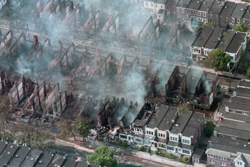 Aerial view of smoke rising from smoldering rubble where 61 homes were destroyed by a fire started by the MOVE bombing in West Philadelphia, May 13, 1985.