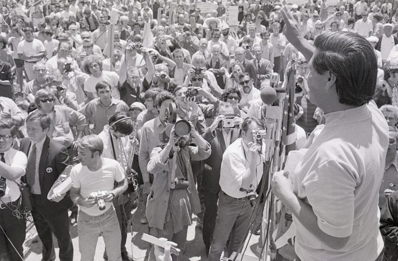  7/25/1970-San Rafael, CA- Cesar Chavez, director of the United Farm Workers Organizing Committee, gives victory sign to over one thousand members of various Northern California unions who staged a peaceful march against the San Rafael independent-Journal in support of the Typographical Union which has been on strike against the Bay Area newspaper for six months. Chavez addressed the crowd during rally at Albert Park and called for a non-violent boycott of the paper.