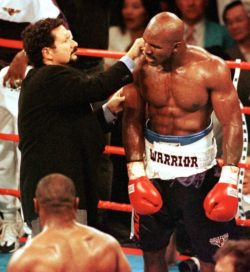 Blood flows down his arm and chest as Evander Holyfield (R) has his ear examined by the ringside doctor 28 June 1997 during his WBA heavyweight championship fight against Mike Tyson at the MGM Grand Garden Arena in Las Vegas, NV. Holyfield won by disqualification in the the third round after Tyson bit him.