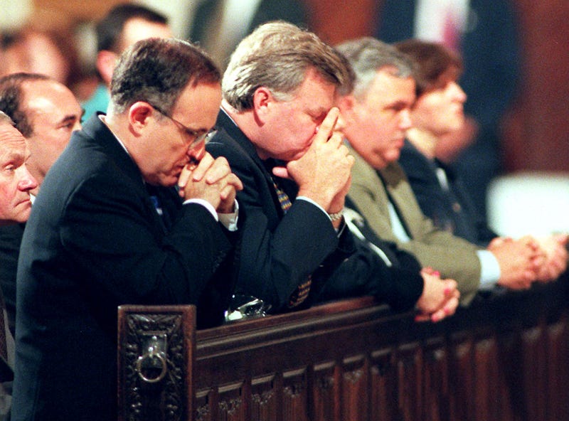 Then-New York Mayor Rudolph Giuliani (L) prays during a memorial service at St. Patrick's Cathedral 17 July during a church service to mark the one year anniversary of the TWA Flight 800 disaster over Long Island in which 230 people died in the explosion.