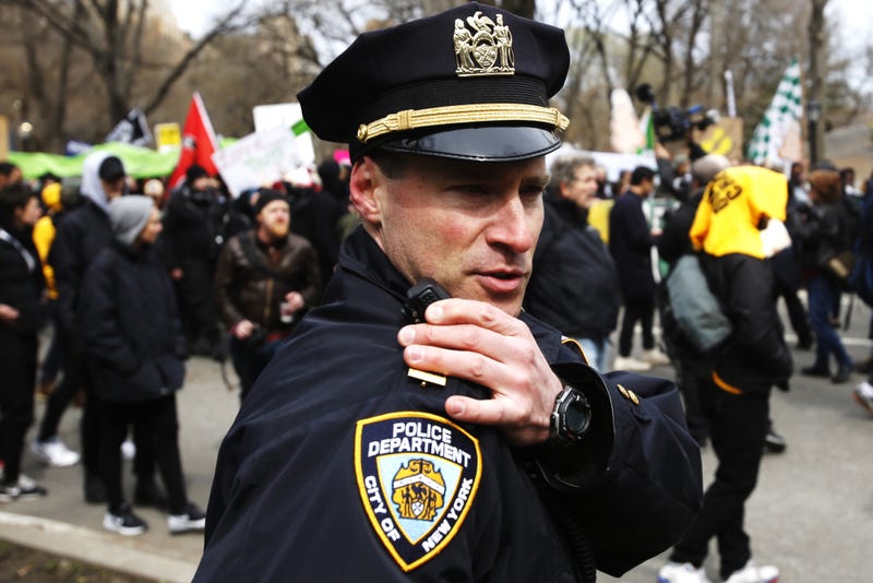 An NYPD officer talks on his radio while people take part in a protest against Donald Trump, on March 19, 2016 in New York City.