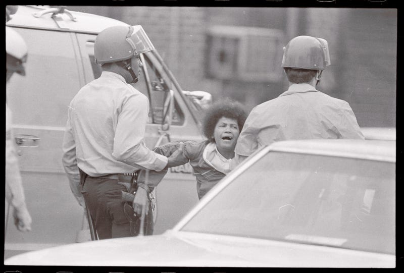 Philadelphia police carry away a MOVE supporter from the scene on May 13, 1985.