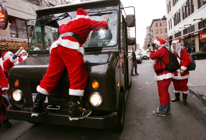 File photo: A Santa Claus climbs on a UPS truck on 44th Street while others participate in Santacon in New York City