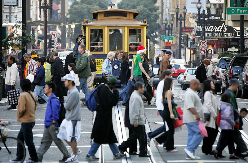 Shoppers pass in front of a cable car as they walk through the Union Square shopping district December 24, 2004 in San Francisco, California.