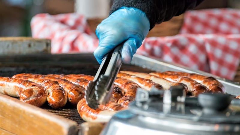 Take away sausages being grilled at public food market stand.
