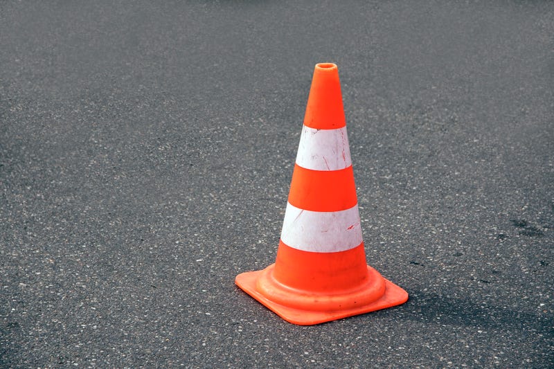 traffic cone, with white and orange stripes on gray asphalt