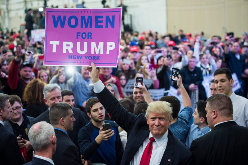 Donald Trump hold up a 'Women for Trump' sign as he greets the crowd after speaking during a campaign event at Grumman Studios in Bethpage, NY on Wednesday April 06, 2016.