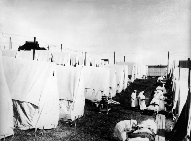 Masked doctors treat flu patients at a hospital camp during the influenza epidemic of 1918.
