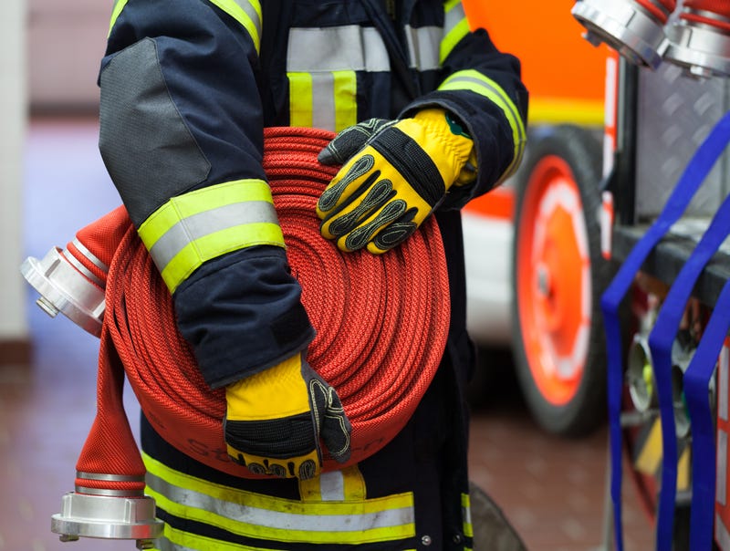 Firefighter holds orange hose