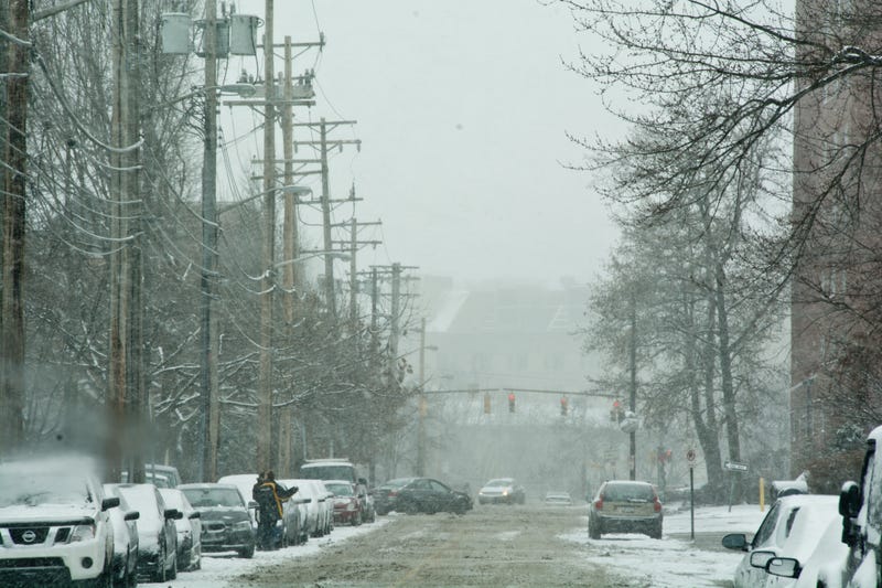 Pedestrians try to hail a cab on this snowy Shadyside street during a major winter storm.