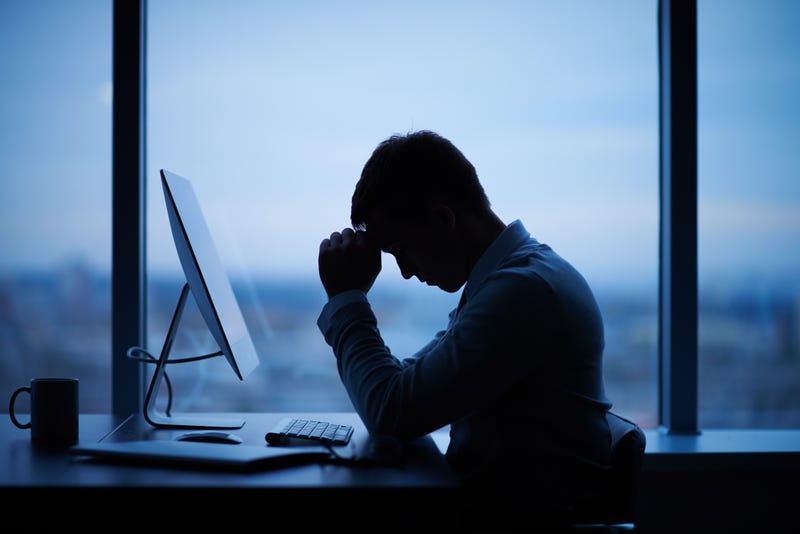 Person working at desk, dark silhouette, showing frustration