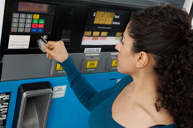 Woman paying with credit card at gas pump.