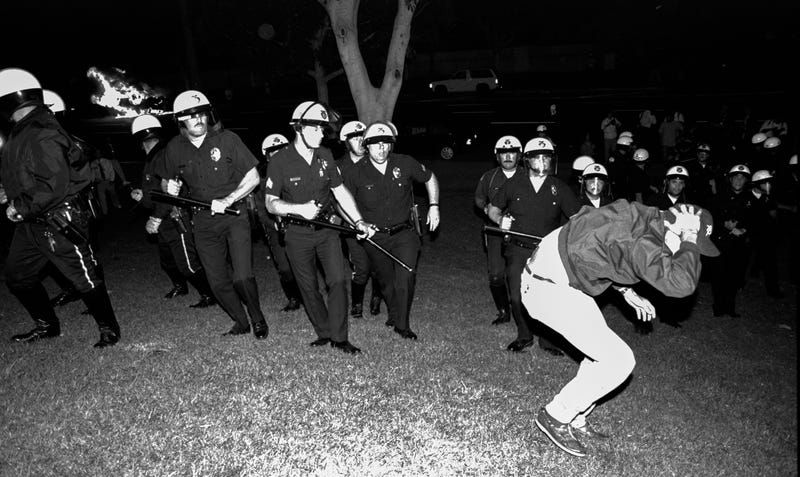 April 29, 1992: Protests against a not-guilty verdict against LAPD officers in the beating of Rodney King transformed into civil unrest. Scan from negative of LAPD officers from Parker Center advance across City Hall lawn against stricken rioter in the early evening.