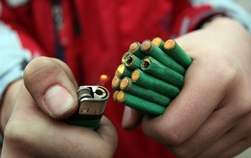 Hands holding fireworks and a lighter.