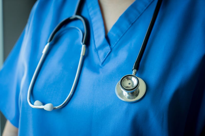 nurse in scrubs with stethoscope around her neck
