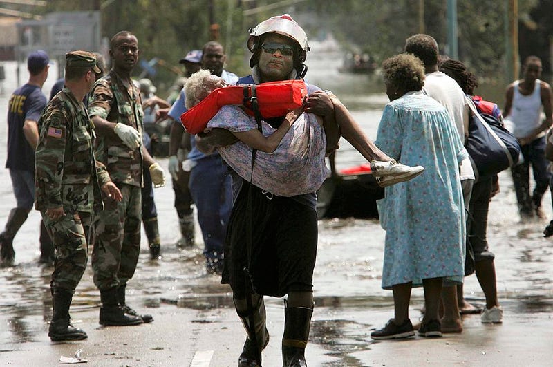 A woman is carried out of flood waters after being trapped in her home in Orleans parish during the aftermath of Hurricane Katrina August 30, 2005 in New Orleans, Louisiana. Katrina made landfall as a Category 4 storm with sustained winds in excess of 135 mph. (Photo by Mario Tama/Getty Images)