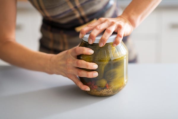 Woman opening a jar of pickled cucumbers