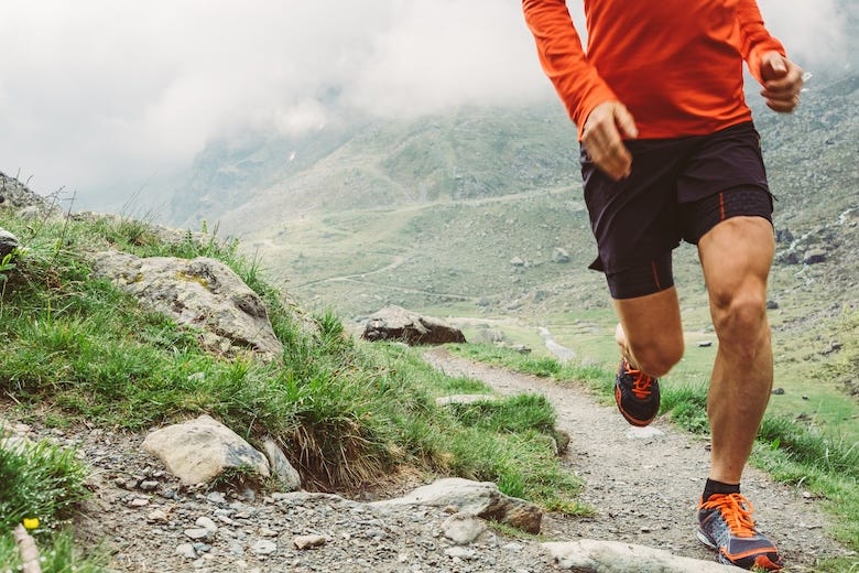 Man running on a trail through a mountain