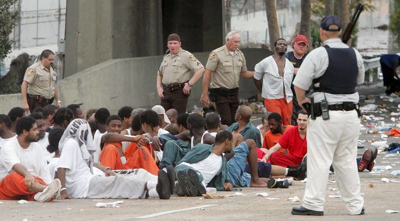 Police watch over prisoners from Orleans Parish Prison who were evacuated from their prison to the highway due to high water September 1, 2005 in New Orleans, Louisiana. Rescue efforts continue as officials in New Orleans fear the death toll from Hurricane Katrina could be in the thousands. (Photo by Mario Tama/Getty Images)