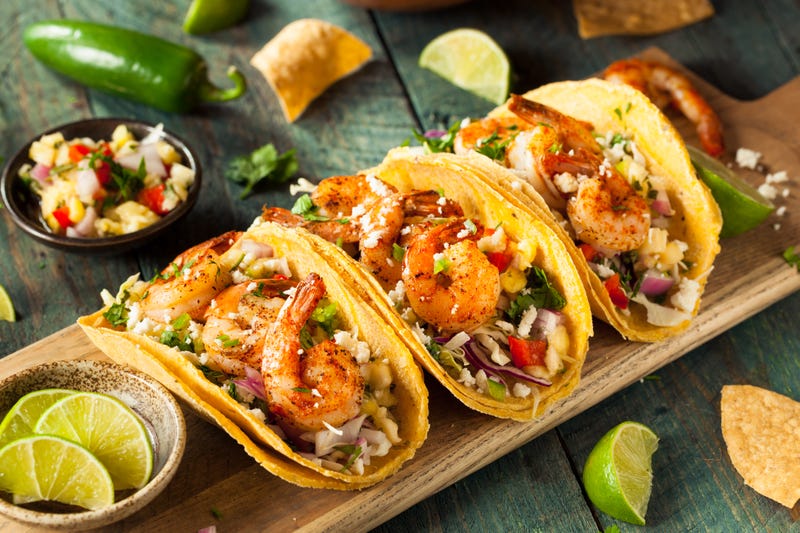 three tacos on a wooden tray