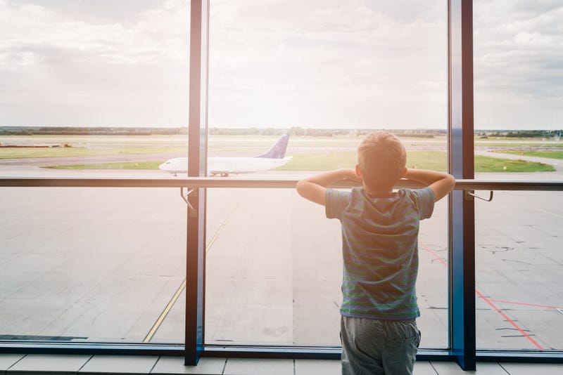 hild at the airport, traveling and waiting near window