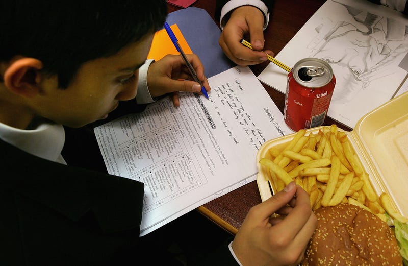 A student eats a hamburger and fries for lunch at school in London, England.
