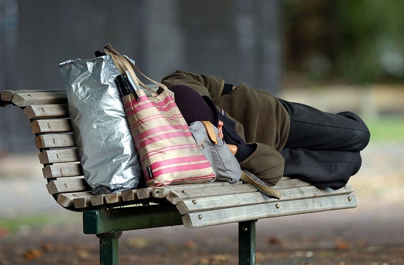 Homeless person sleeping on a park bench at Victoria Park, Auckland.