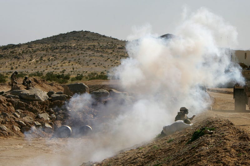 Two civilian Iraqi role players are seen as smoke from a mock IED (Improvised Explosive Device), or roadside bomb, envelops U.S. Marines on a practice urban assault at Range 215 simulated Iraqi village at the Twentynine Palms Marine Base on November 15, 2005 near Twentynine Palms, California. The marines have turned shipping containers into simulated Iraqi villages on Ranges 200 and 215 to train their fighters in an urban environment similar to that which they will be deployed to in Iraq. The Marines will be conducting Stability and Support Operations next year in Iraq with emphasis on training and mentoring Iraqi Security Forces. (Photo by David McNew/Getty Images)