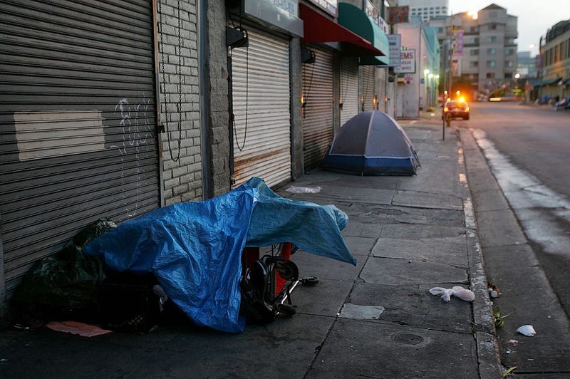 A police car stops near homeless people sleeping in their encampments.
