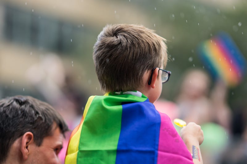 kid with pride flag around his shoulders
