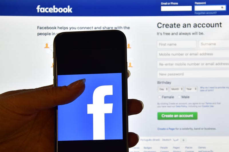  A person holds an iPhone displaying the Facebook app logo in front of a computer screen showing the facebook login page on August 3, 2016 in London, England. 