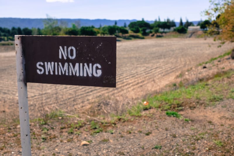 A No Swimming sign outside of a dried up water system in Santa Clara, CA.