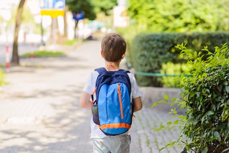 Boy wearing backpack walking to school