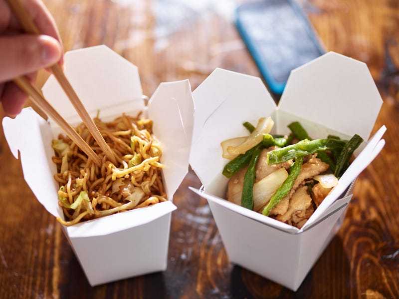 eating lo mein out of chinese take out box wih chopsticks