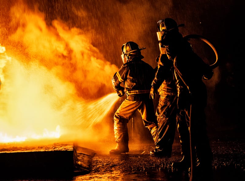 Two firefighters fighting a fire with a hose and water