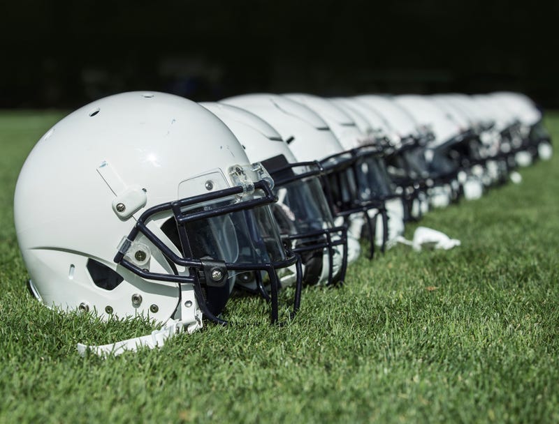 Football helmets in a row on a grassy field