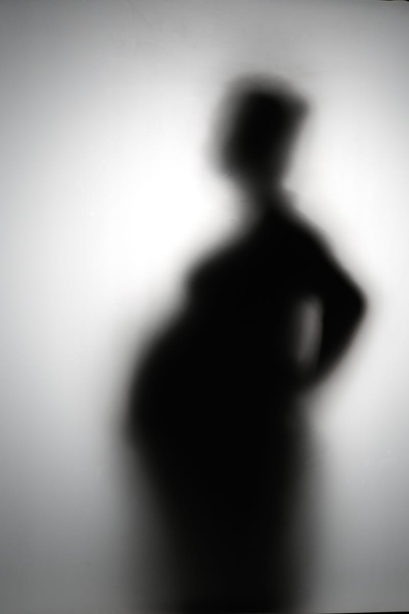 Pregnant woman silhouette, blurred. Stock photo.