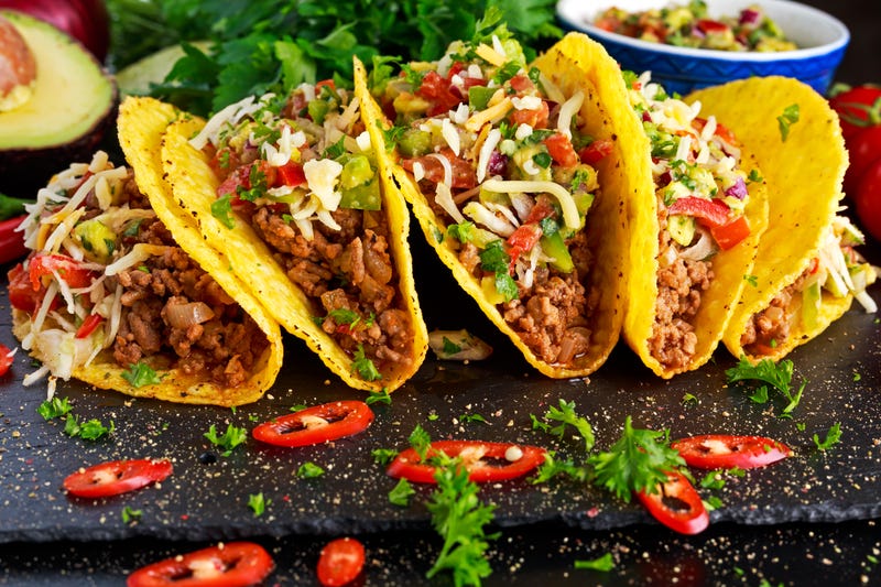 Four tacos with ground beef and toppings in hard tortilla shells