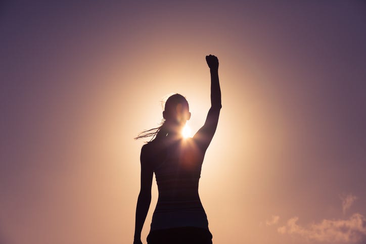 Silhouette of a strong confident woman with fist raised