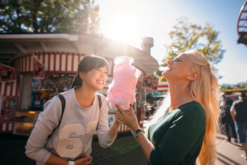 female friends in amusement park eating cotton candy