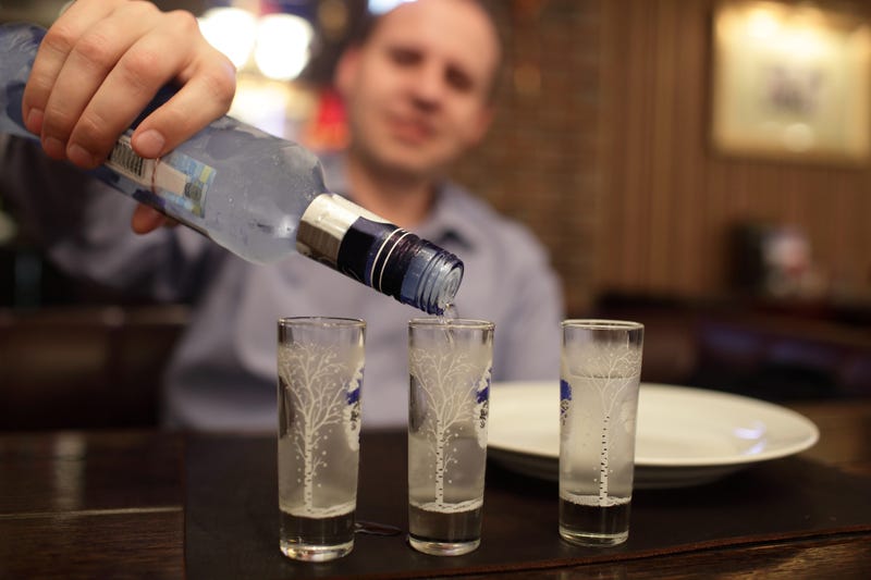 A man pours vodka into shot glasses