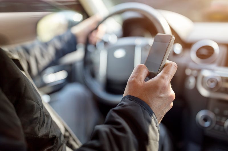 Stock photo of driver using phone behind the wheel