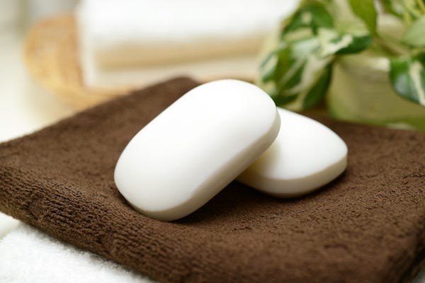 Two bars of soap resting on a brown washcloth
