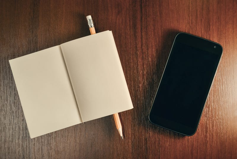 A smartphone next to a notebook